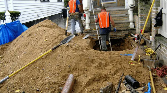 Contractors performing foundation protection and exterior drainage excavation near residential home steps in Indianapolis, IN
